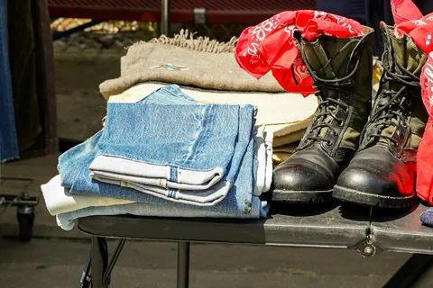 Folded secondhand denim and boots on a resale table